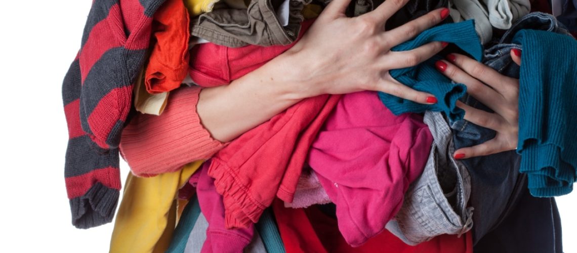 Woman holding a huge pile of clothes